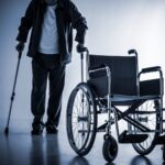 Persona con discapacidad con muletas al lado de una silla de ruedas