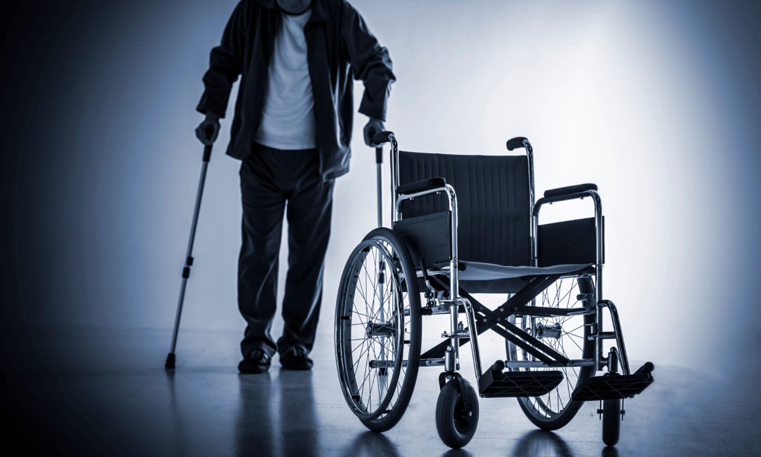 Persona con discapacidad con muletas al lado de una silla de ruedas