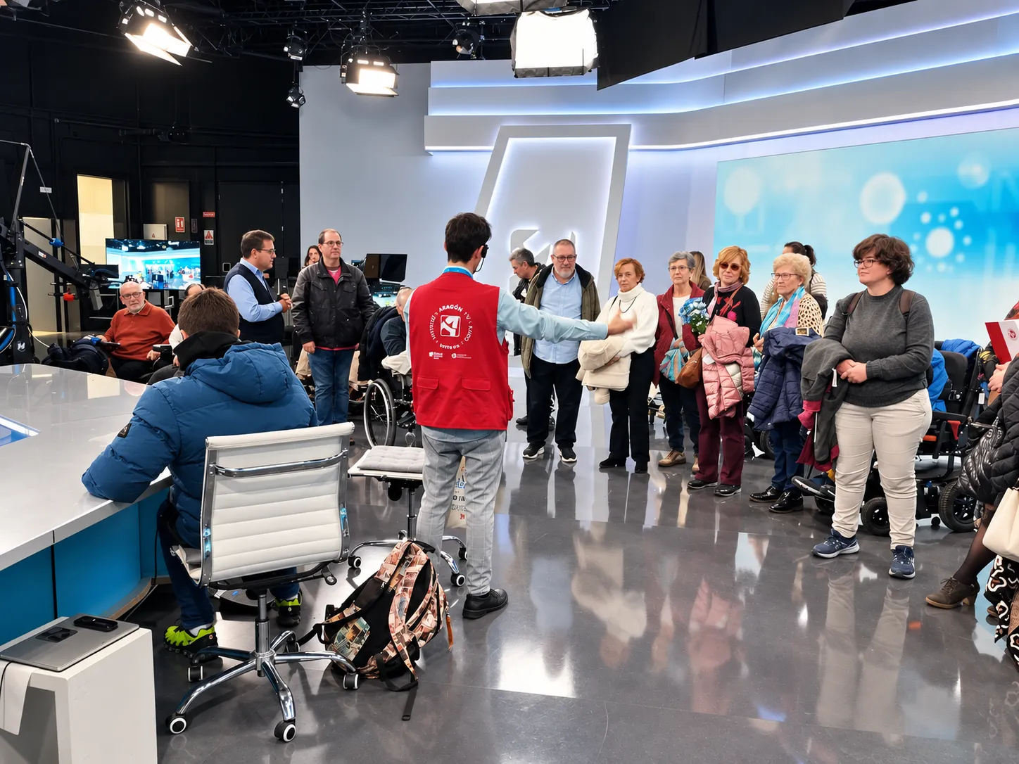 Guia con discapacidad intelectual explicando un plato de televisión a un grupo de visitantes.